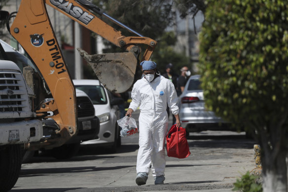 A forensic investigator carries equipment outside the house where police found bones under the floor in the Atizapan municipality of the State of Mexico.