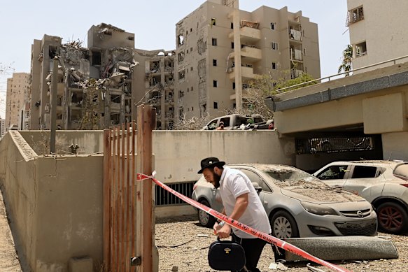 A man walks past the apartment building that was hit by an Iranian ballistic missile that killed four people early on Tuesday morning in Beersheba, Israel. 