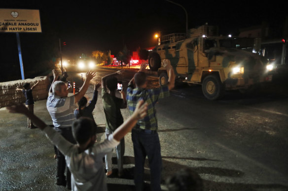 Locals cheer as a convoy of Turkish forces passes on its way to the Syrian border.