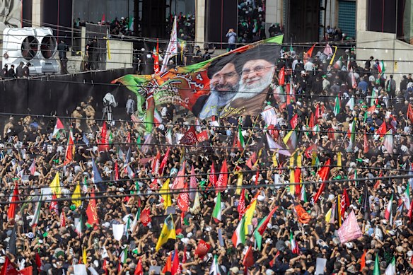 People wave flags at a farewell ceremony for Iran’s late Ayatollah Ali Khamenei.