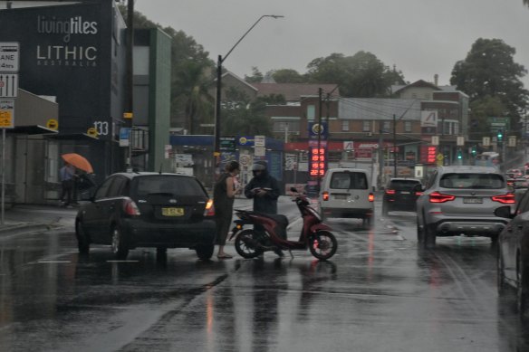 Drivers of a car and scooter exchange details in lanes after an apparent bingle on Victoria Road in Balmain on Tuesday morning.