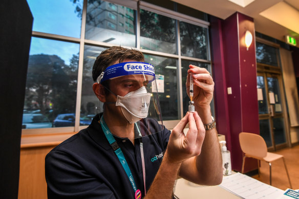 Cohealth nurse Ashley Nind prepares a dose at a pop-up vaccination clinic at the North Melbourne public housing tower that was locked down last year.