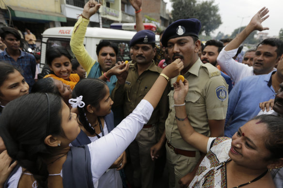 An Indian woman gives a treat to a police officer as the crowd celebrates the police killing of four rape suspects in Shadnagar.