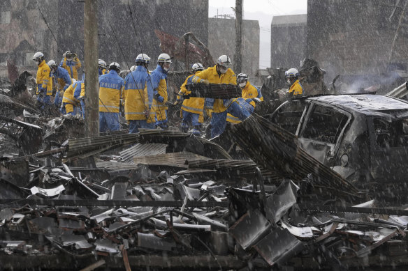 Police officers search through the debris from a fire at a market in Wajima, Ishikawa prefecture on Saturday after a series of powerful quakes set off a large fire.