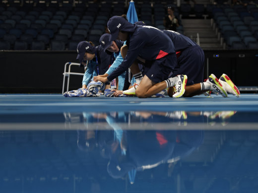 Ball kids dry off the courts after rain stopped play at the Australian Open.