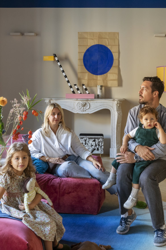 The family on a “Pixel” sofa by SABA. On the fireplace is an “Oceanic” lamp by Memphis Milano and the artwork above it is by Nicolas Denino.