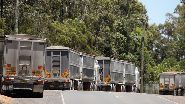 Trucks with NSW licence plates carrying construction waste line up on Sherbrooke Road in Willawong waiting to enter Cleanaway's recycling facility.