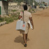 Deborah Sebi carrying immunisations in a refrigerated box on her way to set up the mobile clinic in Teshie, a fishing village near Accra, Ghana.
