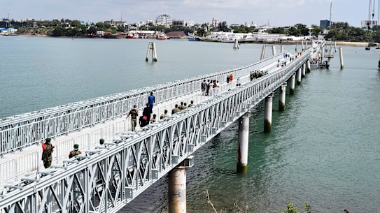 People walk across the newly commissioned Liwatoni floating footbridge in Mombasa, Kenya, another project financed and built by China.