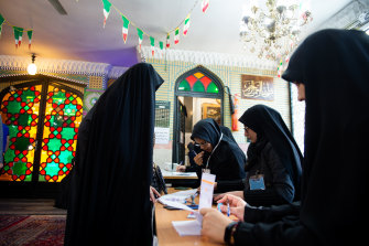 Officials check a voter's ballot papers at a polling station in Tehran, Iran, on Friday.