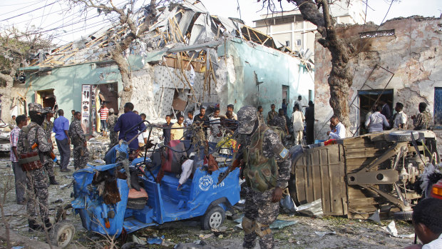 People stand outside a destroyed building after a car bomb in Mogadishu, Somalia, in March. The road has been a target of attacks in the past by the Somalia-based extremist group al-Shabab, the deadliest Islamic extremist group in Africa.