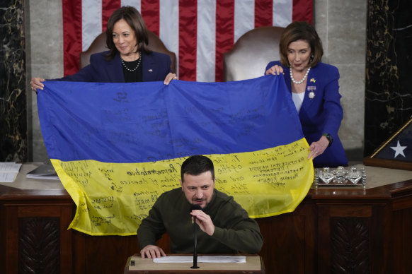 US House Speaker Nancy Pelosi and Vice President Kamala Harris hold open a Ukrainian flag that was presented to them by Ukrainian President Volodymyr Zelensky.