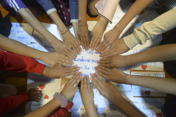 Anti-coup protesters flash the three-finger salute to signify defiance in Yangon, on Monday. They wrote cards thanking other countries for trying to help bring democracy back to Myanmar.