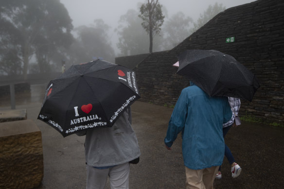 Tourists brave the wet weather at the Three Sisters,  Katoomba on Thursday.
