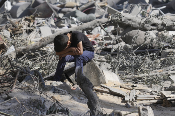 A Palestinian boy sits on the rubble of the building destroyed in an Israeli airstrike in Bureij refugee camp Gaza Strip.