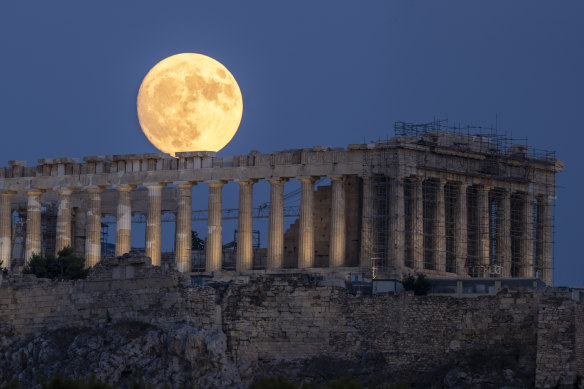 The moon rises in the sky behind the Parthenon at the ancient Acropolis hill, in Athens.