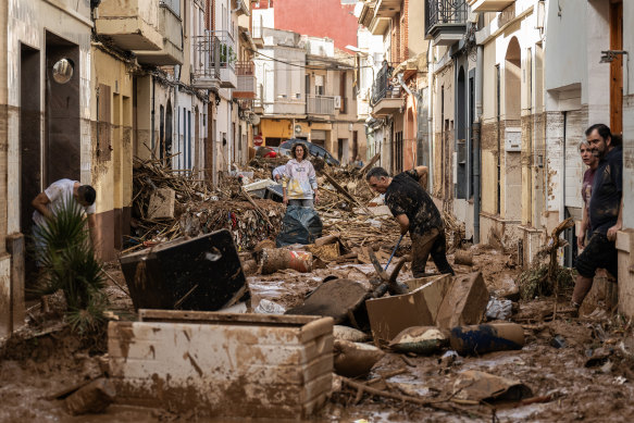 Residents clean up a mud-and-debris-covered street after flooding hit large parts of the country in the Paiporta municipality of Valencia, Spain.