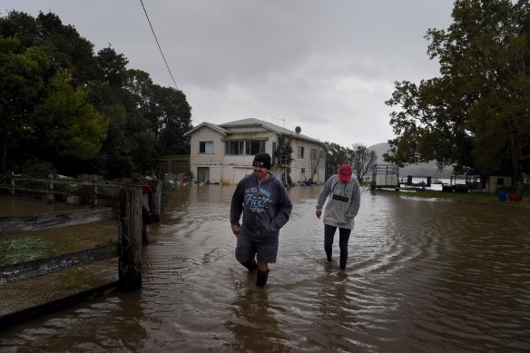 Greg and Amanda Soper walk through the floodwaters on their property near Shoalhaven Heads.