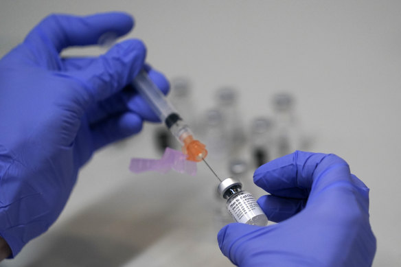 A pharmacy technician loads a syringe with Pfizer’s COVID-19 vaccine.