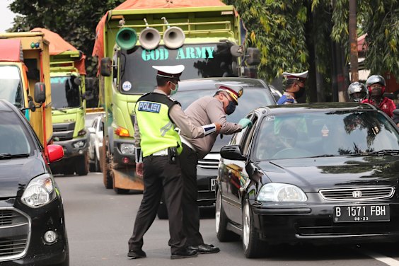 Police officers check the number of people seated inside a car during the imposition of large-scale social restriction, at a checkpoint in Jakarta, Indonesia, on Friday.