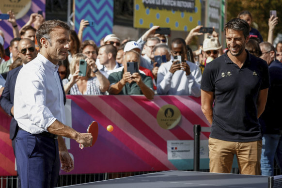 French President Emmanuel Macron plays table tennis while Paris 2024 Olympics Organising Committee President Tony Estanguet looks on at a pre-Games event in Paris.