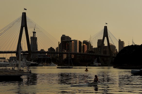 Smoke haze lingers over Sydney as rowers train in Rozelle Bay early on Wednesday morning. 