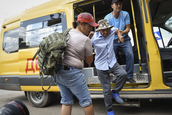 People help evacuate an elderly man from an area near the site of explosion at an ammunition storage of the Russian army in Crimea.