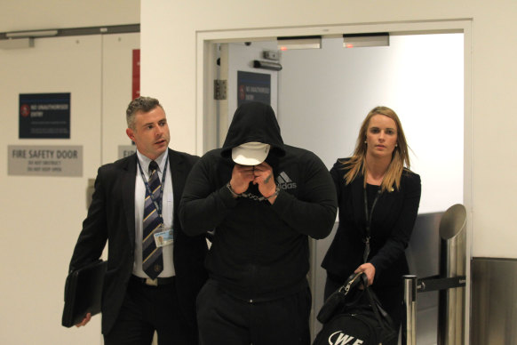 Mahmoud “Brownie” Ahmad, pictured with two detectives, was arrested after he stepped off a flight from Doha in 2017.