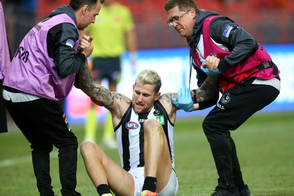 Collingwood's Jeremy Howe is assisted off the field after injuring his knee.