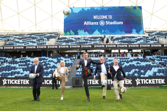 Premier Dominic Perrottet, centre, kicks a ball during the community open day at Allianz Stadium on Sunday.