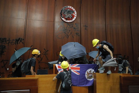 Protesters erect a Hong Kong colonial flag and deface the Hong Kong logo at the Legislative Chamber.