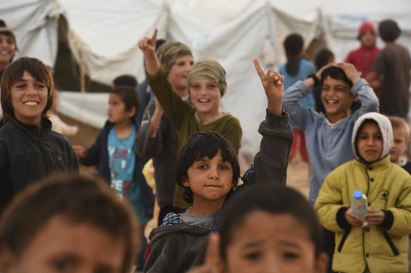 Children at the al-Hawl camp raise their index fingers to the sky in a sign for monotheism adopted by Islamic State followers.
