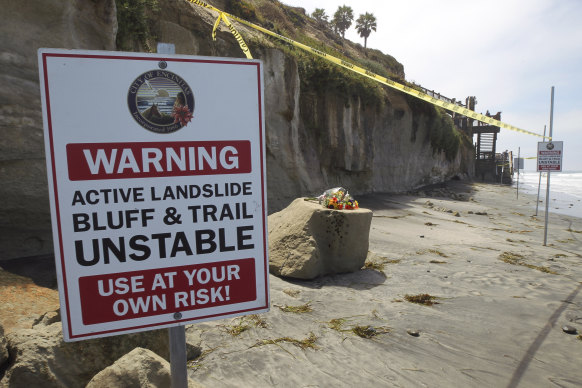 A warning sign posted next to the sand rock debris left from the sea cliff collapse that killed three people near the Grandview Beach access stairway in the beach community of Leucadia, in Encinitas, California. 