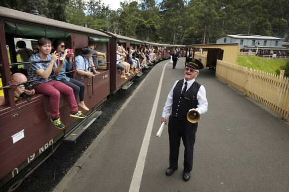 Station master Ian Gibson calls all aboard as passengers let their legs hang out at Belgrave station in 2015. 