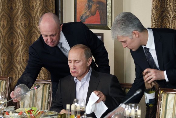 Businessman Yevgeny Prigozhin, left, serves Russian Prime Minister Vladimir Putin, centre, at his restaurant outside Moscow in 2011.