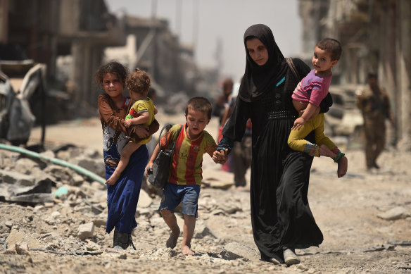 A barefoot boy walks over the rubble with his mum and siblings as they flee the Islamic State in Mosul in 2017.
