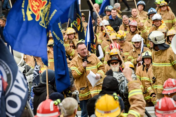 Peter Marshall (centre, with microphone) leads a rally of firefighters in 2016 at Parliament House.