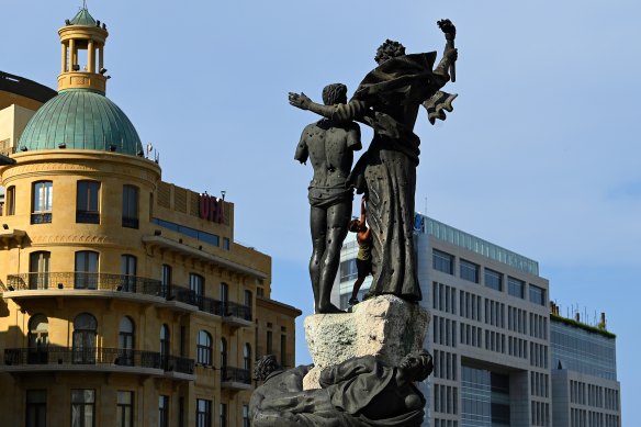 A boy displaced from the southern suburbs of Beirut due to Israeli air strikes stands on the Martyrs’ Statue in Martyrs’ Square in Beirut. 