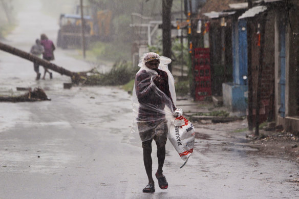 A man covers himself with a plastic sheet and walks in the rain before Cyclone Amphan made landfall.