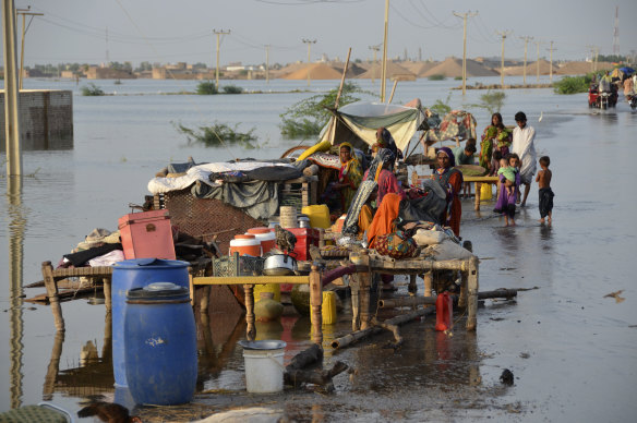 Families sit near their belongings surrounded by floodwaters, in Sohbat Pur city of Jaffarabad. Officials say deaths from widespread flooding have topped 1000 since mid-June.