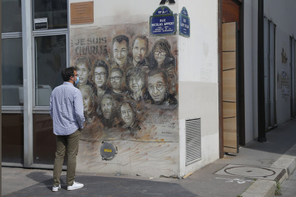 A pedestrian looks at painting by French street artist Christian Guemy, a.k.a. 'C215' in Paris - a tribute to the victims of the satirical newspaper Charlie Hebdo.