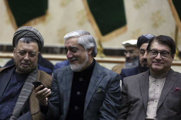 Afghan presidential candidate Abdullah Abdullah (centre) looks at his phone during a press conference in Kabul on Sunday.