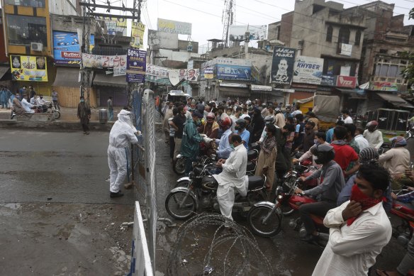 Police officers stop motorcyclists from entering a restricted area that is sealed off to control the spread of the coronavirus in Lahore, Pakistan. 