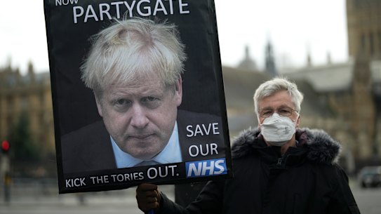 An anti-Conservative Party protester holds a placard with an image of British Prime Minister Boris Johnson.