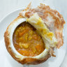 Peel back the lid of the chicken curry pot pie to reveal chunks of chook and vegetables.