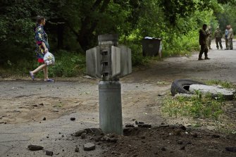 Kostyantynivka şehrinde bir kadın, çöpünü patlamamış bir Rus Smerch roketinin yanından taşıyor. 