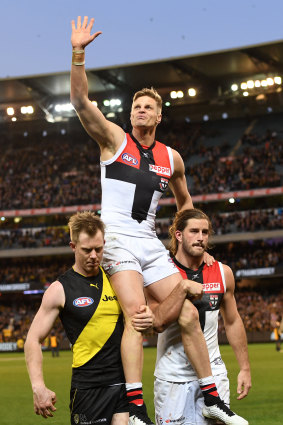 Nick Riewoldt of the Saints (centre) is chaired from the ground by his cousin Jack Riewoldt of the Tigers and Saints teammate Josh Bruce. 