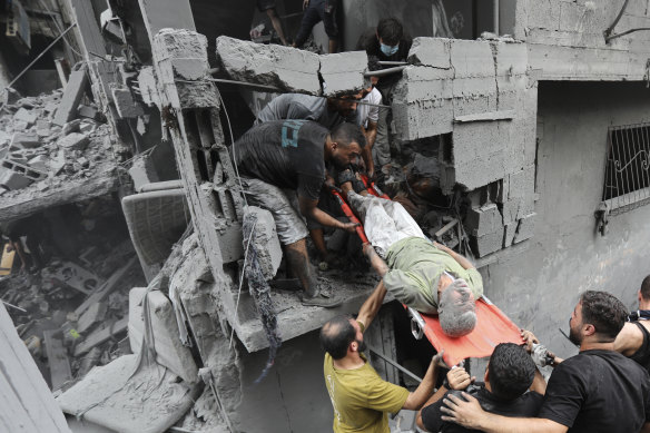 Palestinians carry an injured man from the destruction after Israeli airstrikes on Gaza City on Friday.