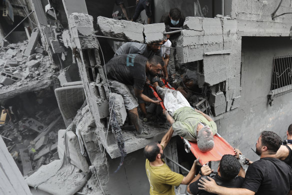 Palestinians carry an injured man out of the destruction following Israeli airstrikes on Gaza City on Friday.