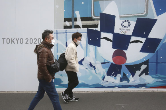 People walk by posters promoting the Olympic and Paralympic Games in Tokyo.